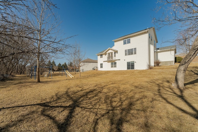 rear view of house with a lawn and a playground