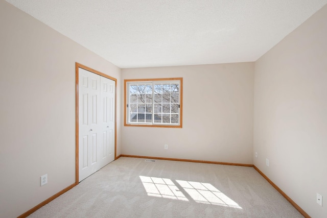 unfurnished bedroom featuring baseboards, carpet floors, a textured ceiling, and a closet