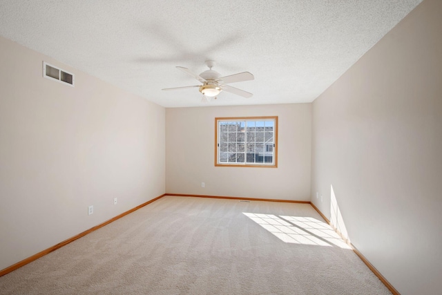 spare room featuring baseboards, visible vents, ceiling fan, a textured ceiling, and light colored carpet