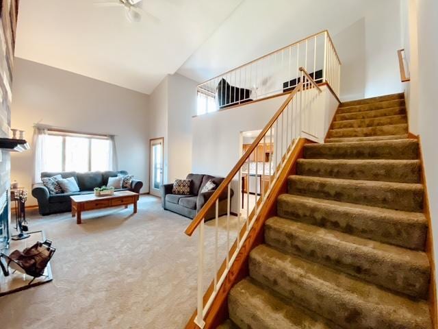 living area with a wealth of natural light, carpet floors, high vaulted ceiling, and stairs