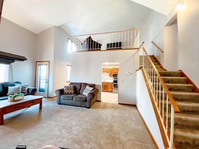 living room featuring stairway, light colored carpet, a high ceiling, and baseboards