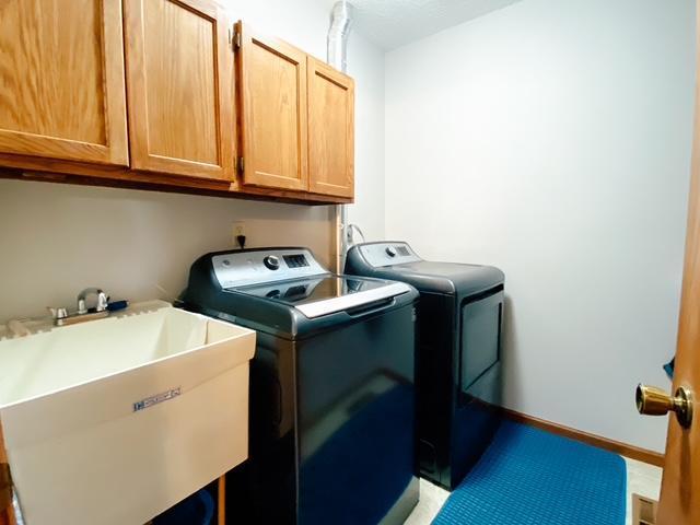 laundry room featuring washer and clothes dryer, cabinet space, baseboards, and a sink