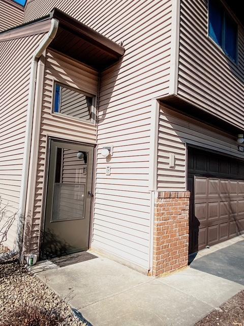 view of exterior entry featuring brick siding and a garage