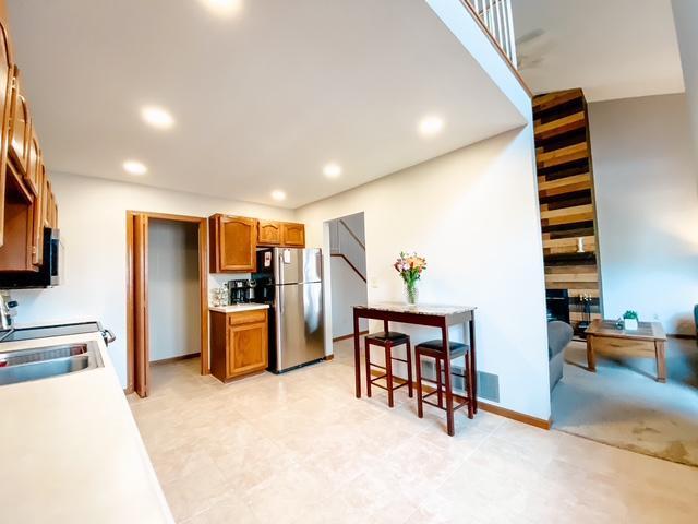 kitchen with light countertops, recessed lighting, brown cabinets, freestanding refrigerator, and stove