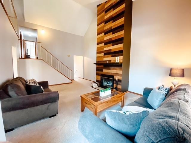 carpeted living area featuring stairway, a fireplace, and high vaulted ceiling