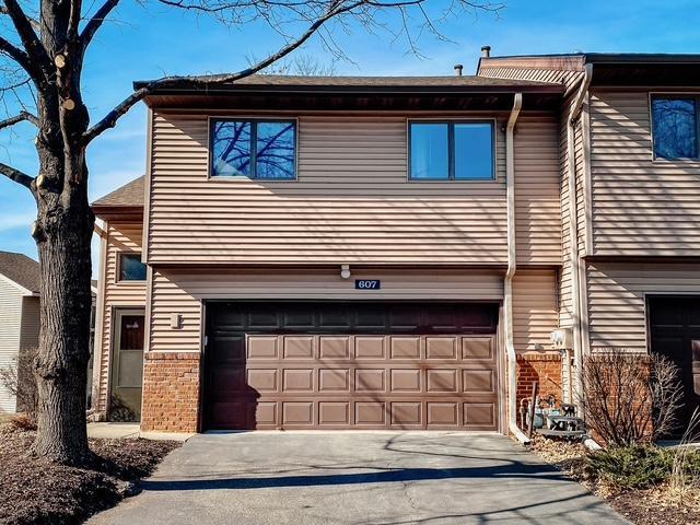 view of property with a garage, brick siding, and driveway