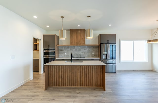 kitchen featuring light countertops, a sink, stainless steel appliances, and decorative backsplash