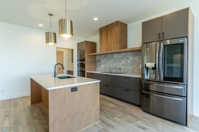 kitchen with decorative backsplash, modern cabinets, stainless steel appliances, a sink, and light wood-type flooring