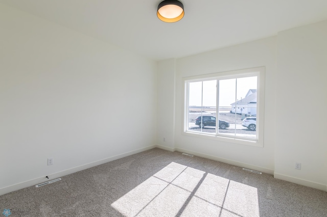 spare room featuring carpet floors, baseboards, and visible vents