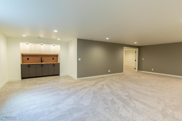 unfurnished living room featuring light carpet, a sink, baseboards, and recessed lighting
