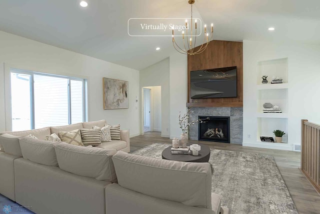 living area with vaulted ceiling, a chandelier, light wood finished floors, built in shelves, and recessed lighting