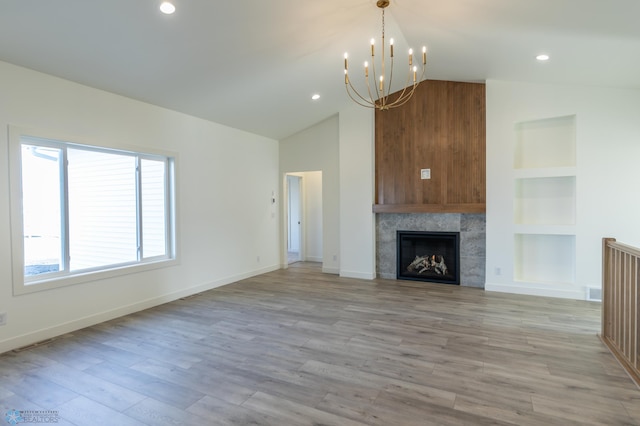 unfurnished living room featuring a notable chandelier, a tile fireplace, built in features, baseboards, and light wood-style floors