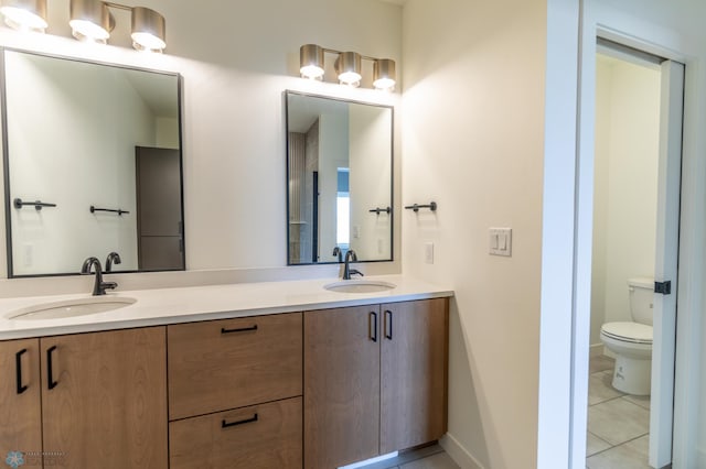 bathroom with double vanity, a sink, toilet, and tile patterned flooring