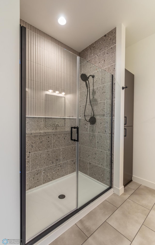 full bath with a shower stall, tile patterned floors, and baseboards