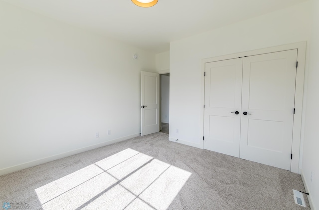 unfurnished bedroom with a closet, baseboards, visible vents, and light colored carpet