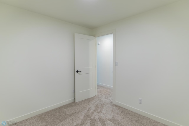 empty room featuring light colored carpet and baseboards