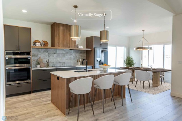8319 59th St S, Horace, ND 58047 - kitchen with open shelves, stainless steel appliances, light countertops, backsplash, and light wood-type flooring