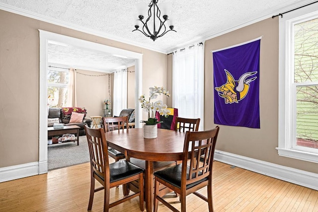 dining space with crown molding, light wood-style flooring, baseboards, and a textured ceiling