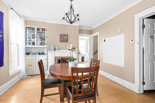 dining space with a textured ceiling, light wood-style floors, baseboards, and a chandelier