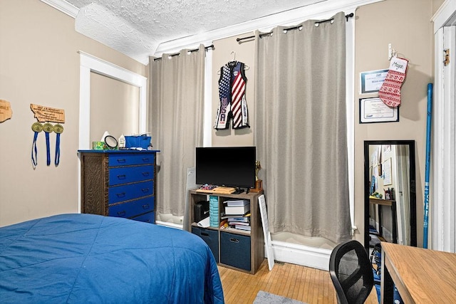 bedroom with a textured ceiling and wood finished floors