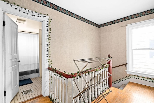 stairway featuring visible vents, wood finished floors, and wallpapered walls