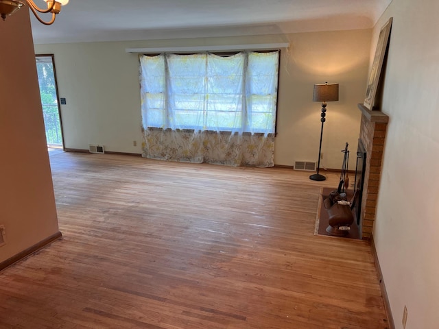 1711 Winnetka Ave N, Golden Valley, MN 55427 - spare room featuring a chandelier, plenty of natural light, a brick fireplace, and wood finished floors