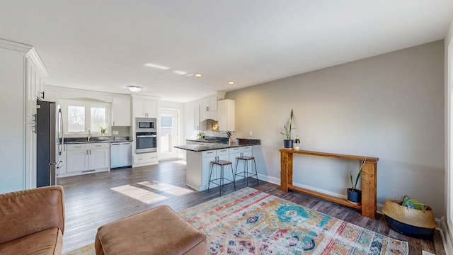 kitchen featuring dark wood-type flooring, white cabinets, appliances with stainless steel finishes, dark countertops, and open floor plan