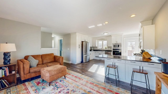 living room with recessed lighting, dark wood-style flooring, and baseboards