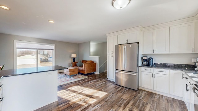 kitchen with dark wood-type flooring, dark stone counters, recessed lighting, freestanding refrigerator, and white cabinetry