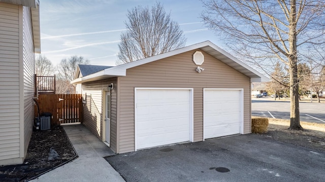 detached garage featuring cooling unit and fence