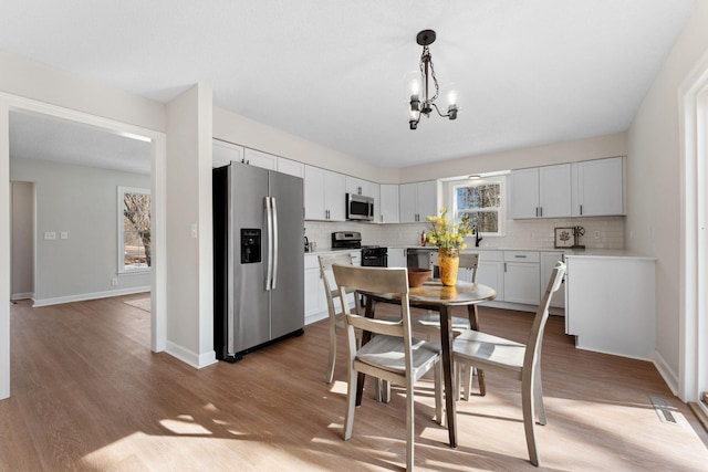 dining space featuring a chandelier, baseboards, and light wood-style floors