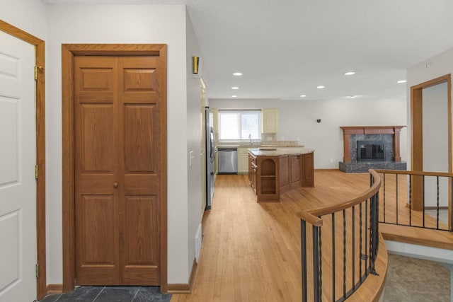 kitchen featuring a high end fireplace, recessed lighting, stainless steel appliances, light wood finished floors, and light countertops