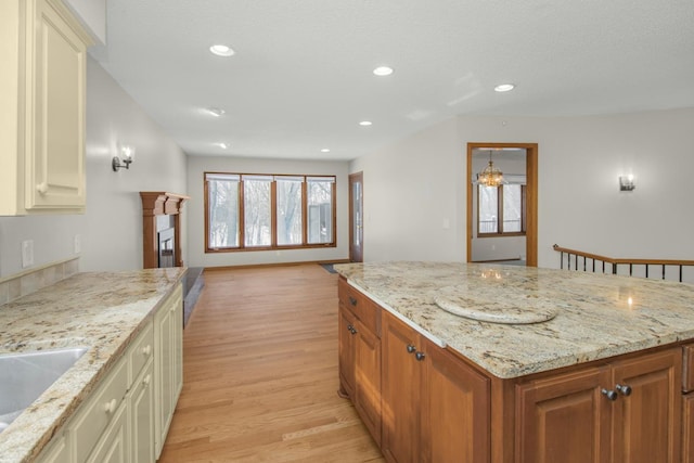 kitchen featuring a wealth of natural light, recessed lighting, light wood-style floors, and light stone countertops