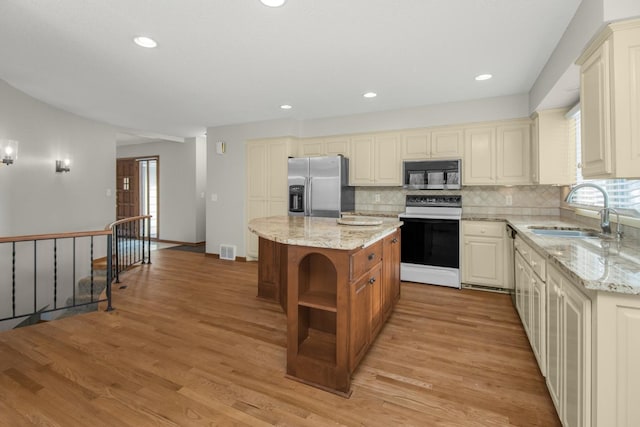 kitchen with visible vents, decorative backsplash, light wood-style floors, stainless steel appliances, and a sink