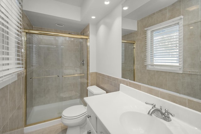 bathroom featuring a shower stall, toilet, vanity, recessed lighting, and tile walls