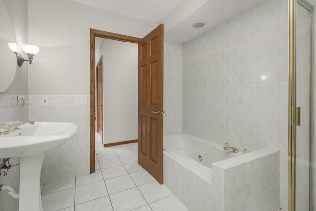 bathroom with walk in shower, tile patterned floors, a tub with jets, tile walls, and a sink