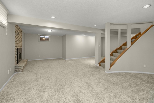 below grade area featuring stairway, carpet, a fireplace, and a textured ceiling