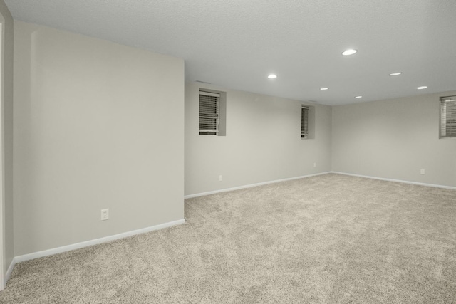 empty room with recessed lighting, light colored carpet, a textured ceiling, and baseboards