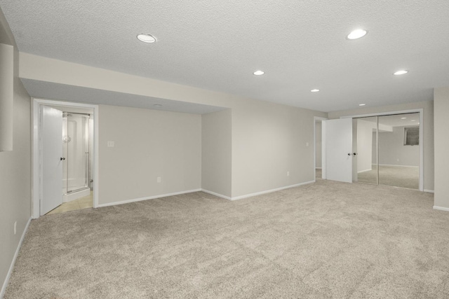 interior space featuring recessed lighting, light colored carpet, a textured ceiling, and baseboards