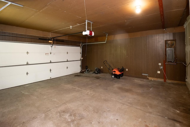 garage featuring electric panel, wood walls, and a garage door opener