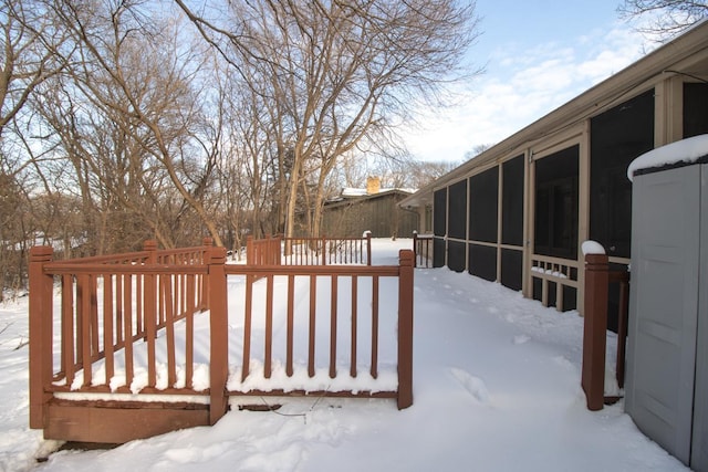 yard layered in snow featuring a deck and a sunroom