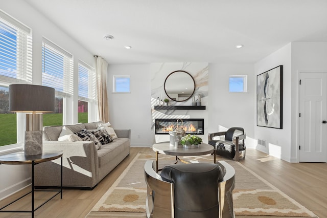 living area featuring recessed lighting, wood finished floors, baseboards, and a large fireplace