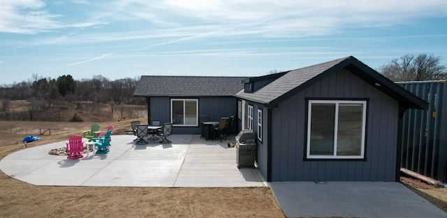 rear view of property with a patio, board and batten siding, and a shingled roof