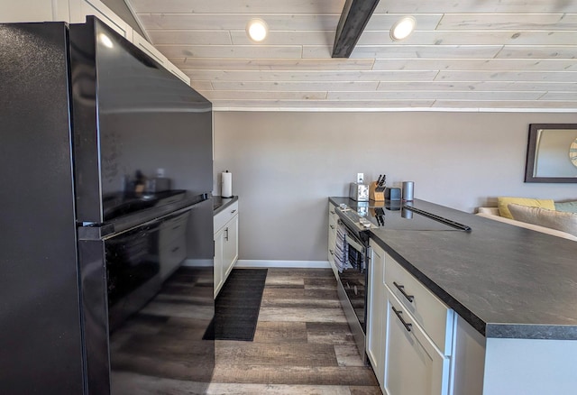 kitchen with dark countertops, stainless steel range with electric stovetop, white cabinets, and freestanding refrigerator