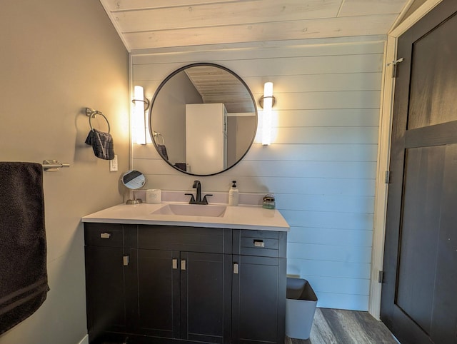 bathroom featuring wooden walls, wood ceiling, wood finished floors, and vanity