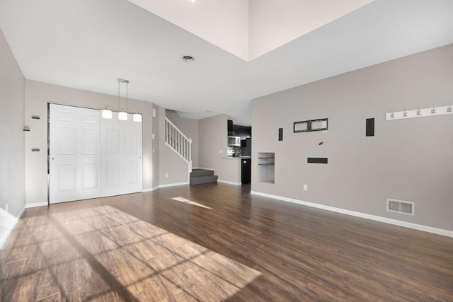 foyer entrance with dark wood-style floors, stairway, baseboards, and visible vents