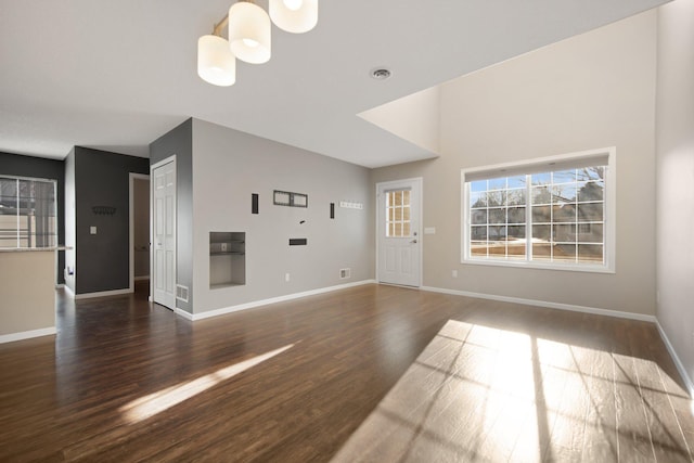 unfurnished living room with baseboards and dark wood-type flooring