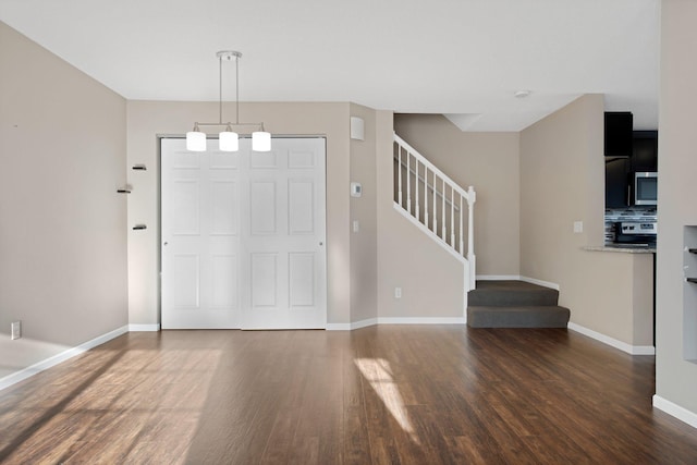 foyer entrance with stairs, wood finished floors, and baseboards