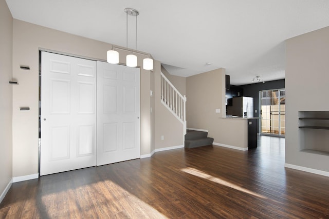 unfurnished living room featuring stairs, baseboards, and dark wood-style flooring