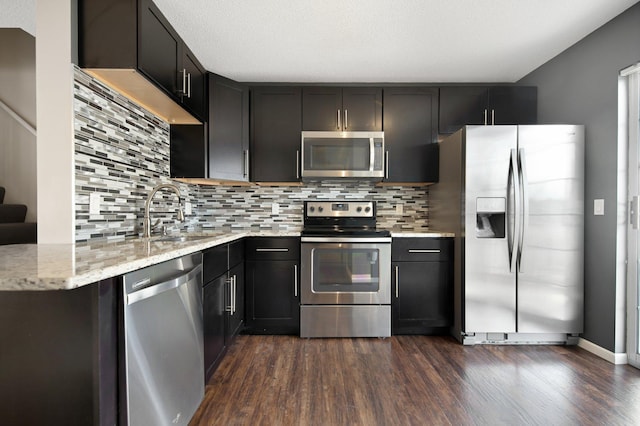 kitchen with a sink, backsplash, appliances with stainless steel finishes, and dark wood-style flooring